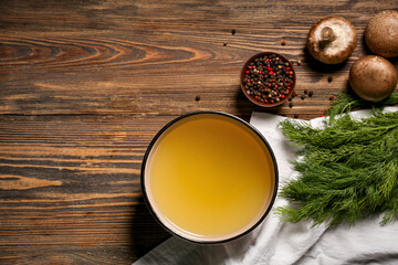 Bowl of tasty vegetable broth and ingredients on wooden background