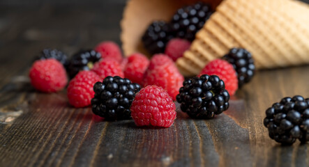 Red ripe raspberries with waffle cups on a black table
