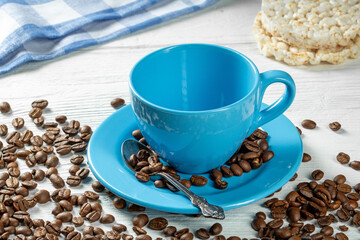 Symbol of morning coffee - an empty blue cup with a saucer for coffee on a white wooden table