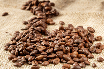 Heap of roasted coffee beans on burlap background close-up