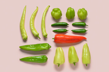 Different fresh peppers on pink background