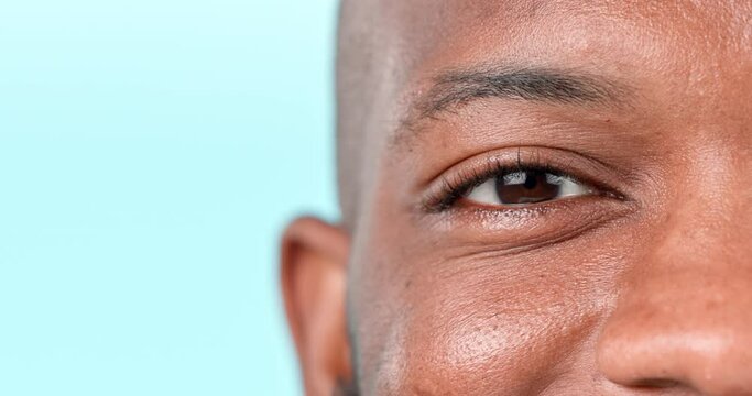Eye, closeup and face of black man with vision, contact lenses or optometry healthcare in studio or blue background. Eyes, wellness and portrait of person with eyesight test, exam or medical check