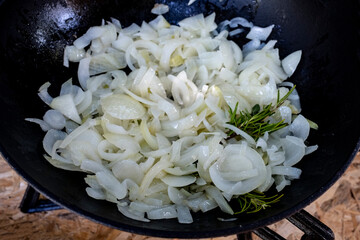 preparing the Hungarian dish goulash in a cast iron pot and on a gas burner, one of the photos in...