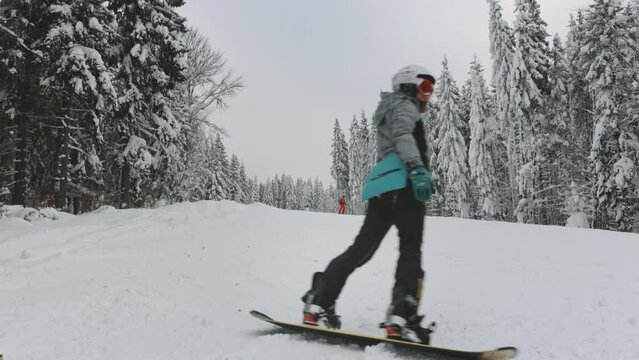 Woman snowboarding on ski slopes in foggy forest. Travel, tourism, holiday, sports, active lifestyle. Bukovel ski resort, Carpathians, Ukraine. Slow motion