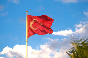 Turkish flag waving flapping with trees and blue cloudy sky background. National holiday Turkish flag concept background.