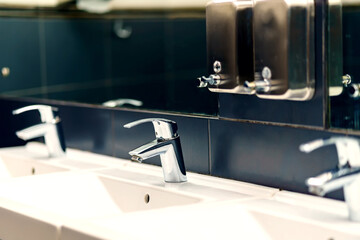 Hand wash basins, mirror, liquid soap dispenser in a public toilet
