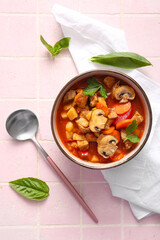 Bowl of tasty beef stew on pink tile background