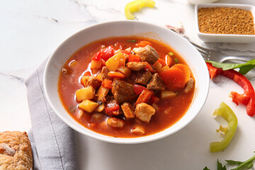 Bowl of tasty beef stew on white marble background