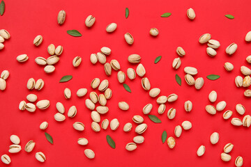 Tasty pistachio nuts and leaves on red background