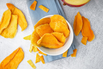 Bowl with slices of dried mango on white background