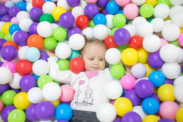 The child has fun in the children's dry pool with colorful balls.