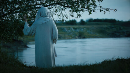Jesus Christ meditate alone by the river Jordan at evening.