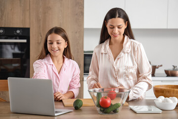 Happy mother with her little daughter cooking breakfast in kitchen