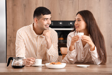Happy young couple having breakfast in kitchen