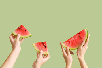 Female hands with slices of fresh watermelon on green background