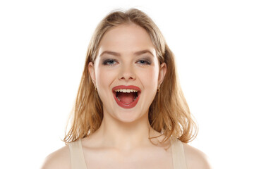 Portrait of young happy blonde woman with open mouth on white background