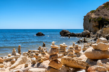 Unzählige zu Steintürmen gestapelte Steine in einer Bucht an der Algarve