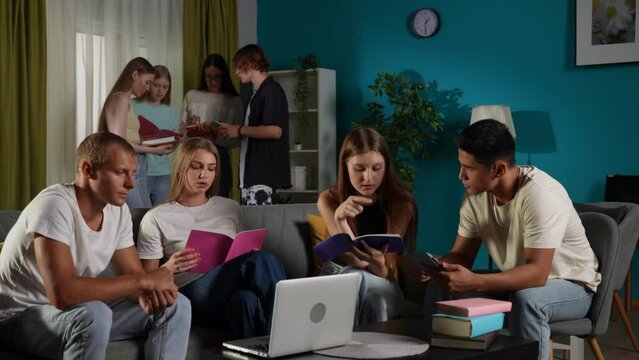 Medium video of a group of teens, young people, friends studying, preparing for an exam, discussing, looking at their notes, using devices, watching something.