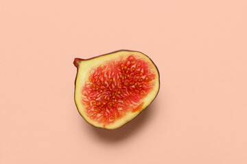 Half of fresh juicy fig on pale pink background