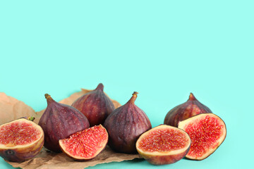 Paper with fresh juicy cut figs on turquoise background