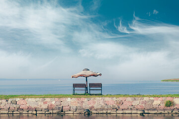 straw umbrella with benches on the shore of the bay  