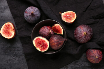 Bowl with fresh ripe figs on black background
