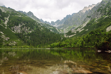 Breathtaking view of the mountains on a hiking trail, among the forest, and an alpine lake. Location of the High Tatras Mountains, Europe. Nature concept, views.