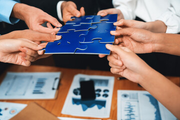Multiethnic business people holding jigsaw pieces and merge them together as effective solution...