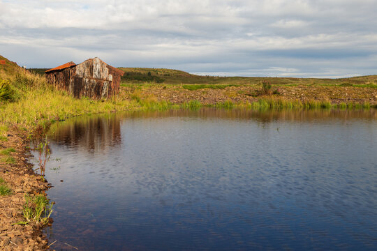 A ruin of a shack on the edge of a loch in Scotland on a sunny summers morning