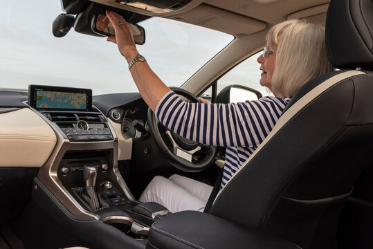 Southsea, Portsmouth, England, UK. 29 August 2023. Lady driver adjusts the rear view mirror from her driving position in her luxury car.