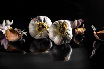 Algumas cabeças de alho sobre uma superfície preta reluzente.