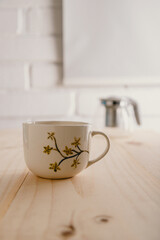 ceramic tea mug with painted flowers and empty teapot on blurred background