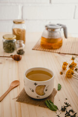 Tea ritual on golden hour with ceramic mug, teapot, flowers, and ingredients