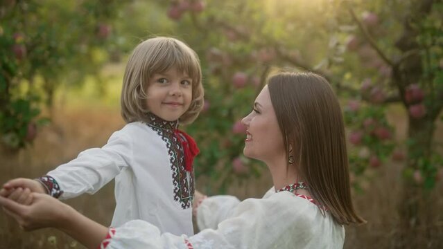 Tender scene of loving son with mom on apple garden backdrop with sunlight. Beautiful family. Cute 4 years old kid with mother. Parenthood, childhood, happiness, children wellbeing concept.