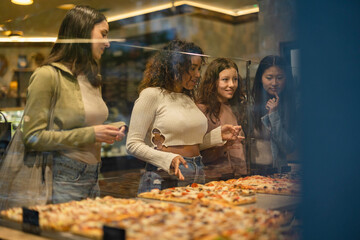 Obraz na płótnie Canvas group of women in an Italian restaurant choosing pizza - takeaway -