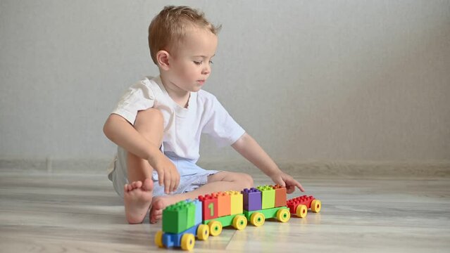 the kid is playing a train with trailers from the constructor with cubes with numbers. Leisure and education of the child