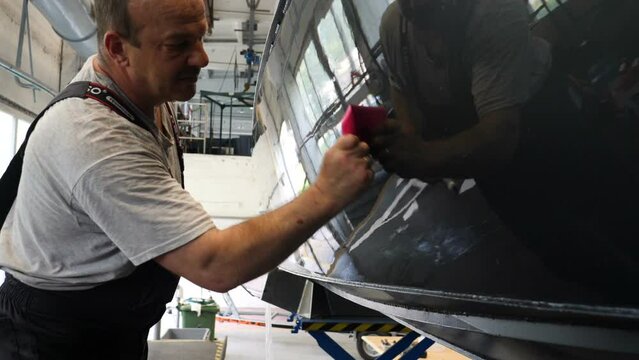 Young handsome professional guy (male) cleaner, washes the yacht after polishing and lining ceramics on the yacht. Concept of: Ceramics, Cleaning, New Ship, Polishing, Cleaner, In Robe, Cap, PPF