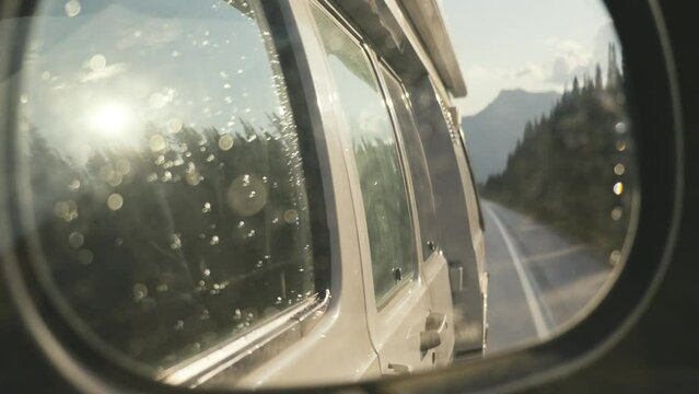 Reflection in the side mirror of an RV driving in Jasper National Park in Canada, during sunrise hours  