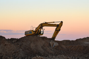 Excavator on earthmoving at open pit mining. Backhoe dig sand, gravel in quarry on sunset. Heavy...