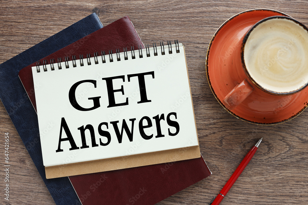 Poster get answers. business concept. open notebook on a wooden table on two notebooks.orange mug with coff