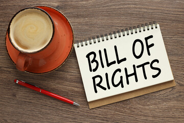 BILL OF RIGHTS top view on a wooden table. mug and notepad with text