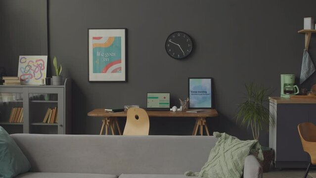 No People Shot Of Modern Room Interior In Minimalist Style At Daytime With Grey Walls, Couch, Bookcase And Wooden Desk With Laptop And Framed Motivational Poster