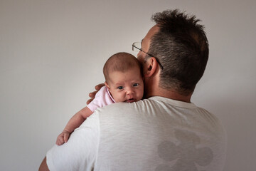 rear view of the father back holding newborn baby on his shoulder