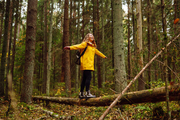 Traveler female with a backpack walks along a wooden footpath in the thicket of a forest. Travel,...
