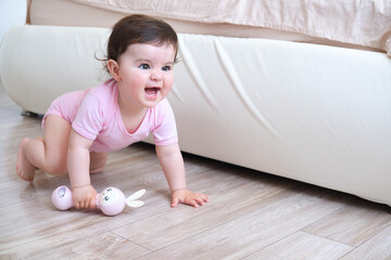 cute smiling baby with plastic bunny toy learns to crawl