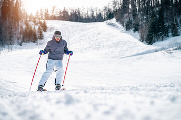 Confident experienced male skier skiing downhill in the mountains. Male skier in movement. Young...
