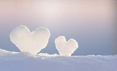 Two hearts made of snow against the evening sky, romantic winter background