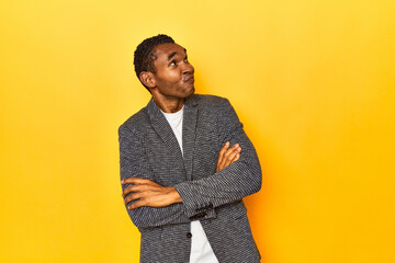 African American man in casual blazer, yellow studio, dreaming of achieving goals and purposes