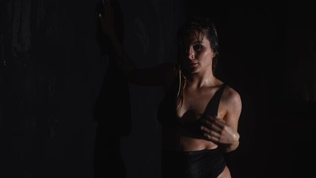 Beautiful woman stand under rain shower in aqua studio slow motion isolated on black studio background. Aqua studio 4k video slow motion 120 fps raw footage