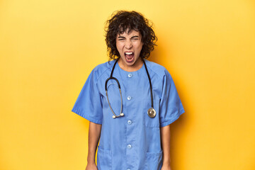 Curly-haired Caucasian woman nurse on yellow studio screaming very angry and aggressive.